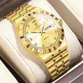 A gold-tone stainless steel wristwatch with a matching metal link bracelet, presented in a light beige watch box. The watch features a textured bezel, a gold dial with crystal hour markers, and a date window.